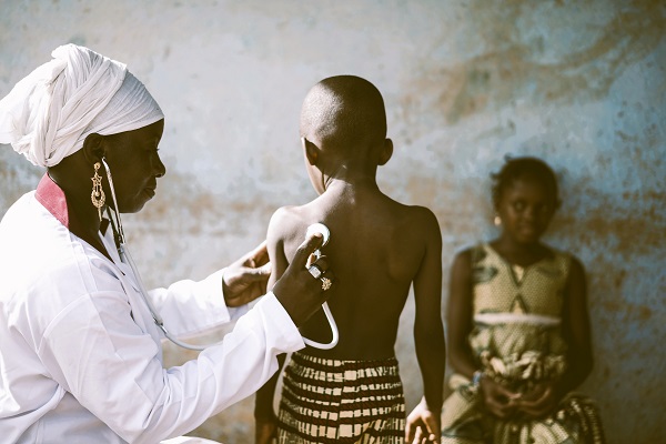Un médecin en Afrique effectue un bilan de santé sur un enfant, ce qui témoigne de l'importance des associations pour l'amélioration de la santé dans le monde.