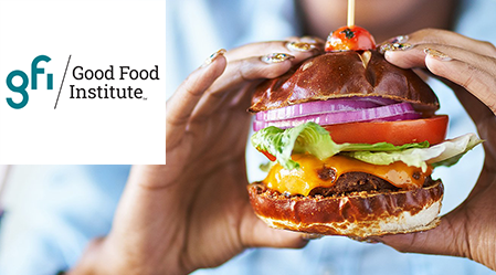 Mains tenant un hamburger végétal avec le logo du Good Food Institute dans le coin.