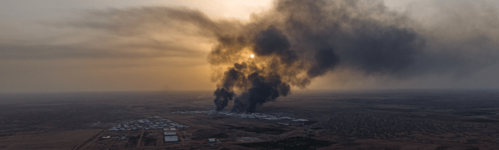 Photo évoquant les risques existentiels: colonne de fumée montant dans un soleil couchant