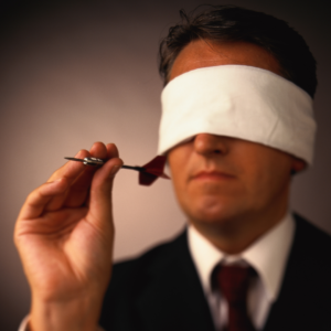 Un homme, les yeux bandés, s'apprête à lancer une fléchette