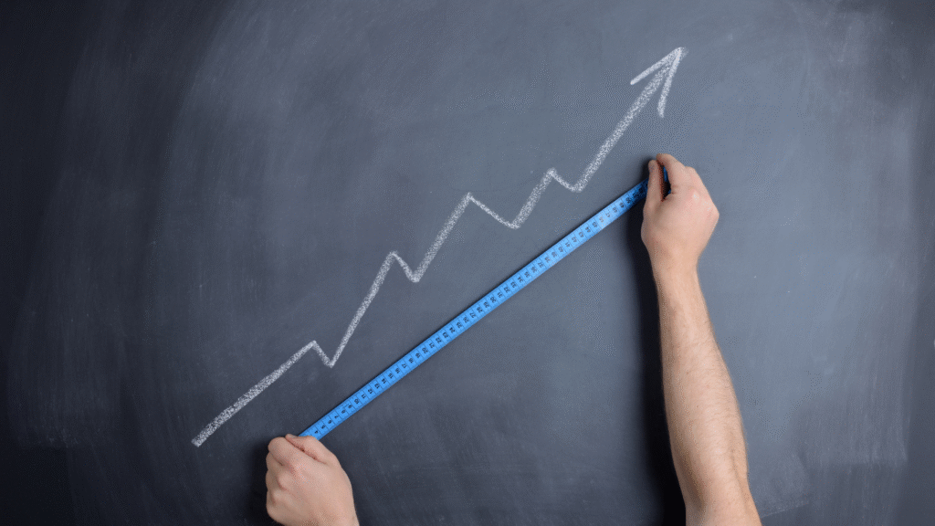 Une flèche dessinée en diagonale sur une ardoise. Une paire de main en mesure la longueur