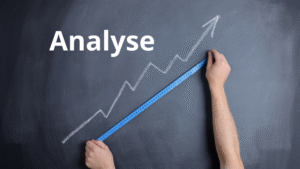 Une flèche dessinée en diagonale sur une ardoise. Une paire de main en mesure la longueur